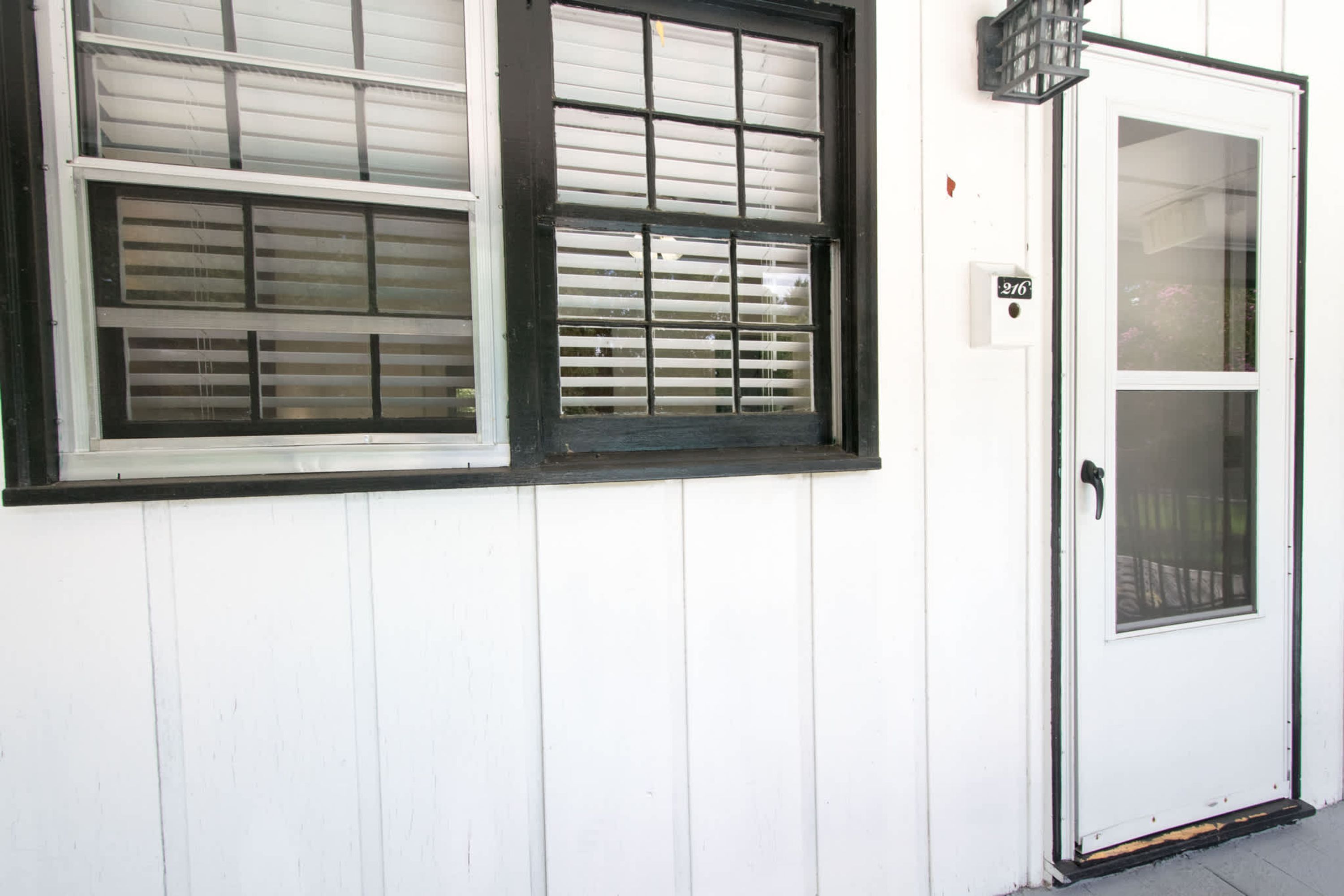 A white building with two windows and a door.