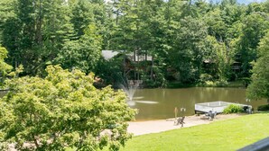 A lakeside view with a dock, a small boat, and a gazebo. - Lakeview 1BR Condo w Deck Walk to Village (Flat Rock)