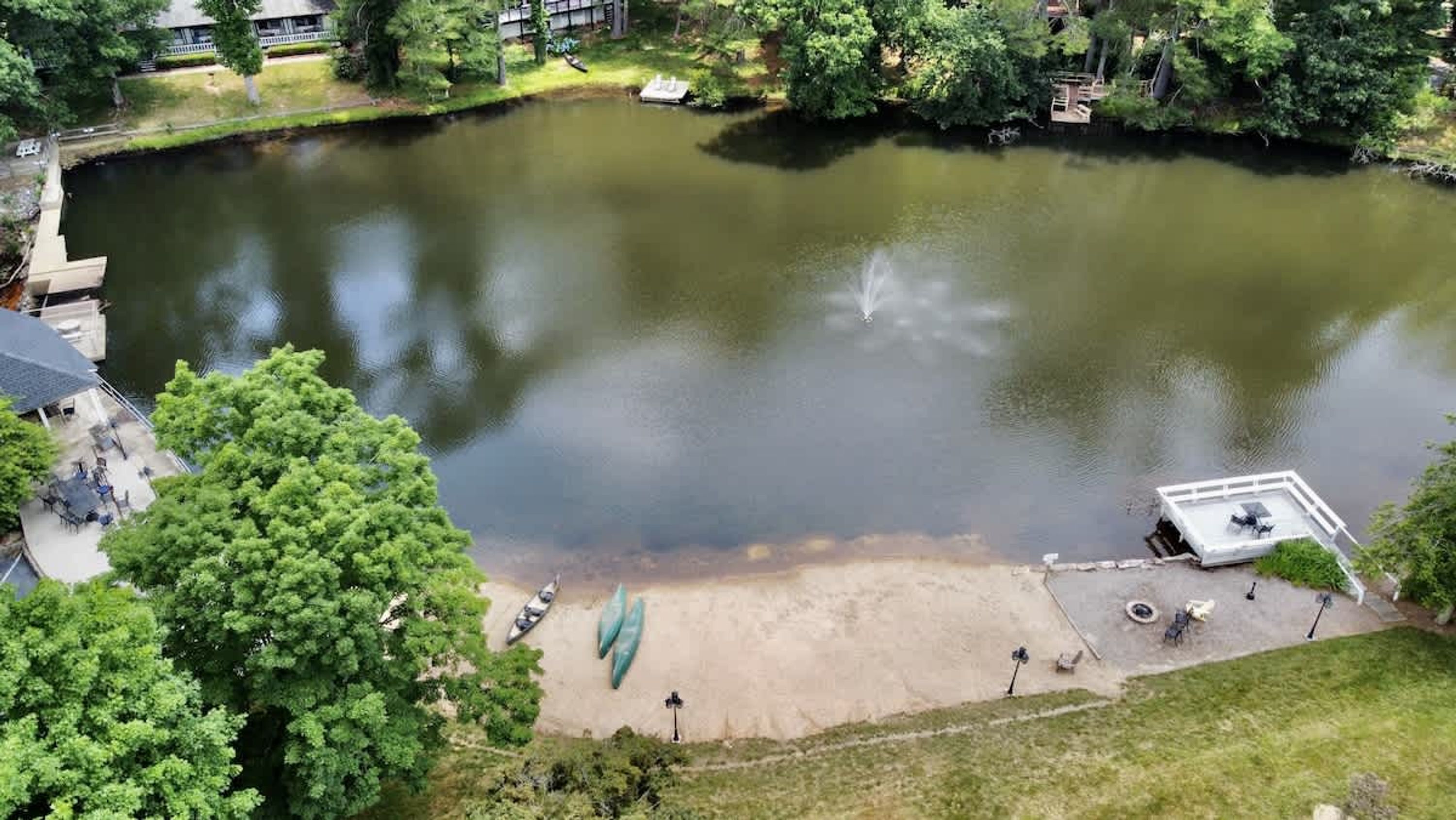 Vue aérienne d’un parc avec un étang, une jetée et un petit bâtiment.