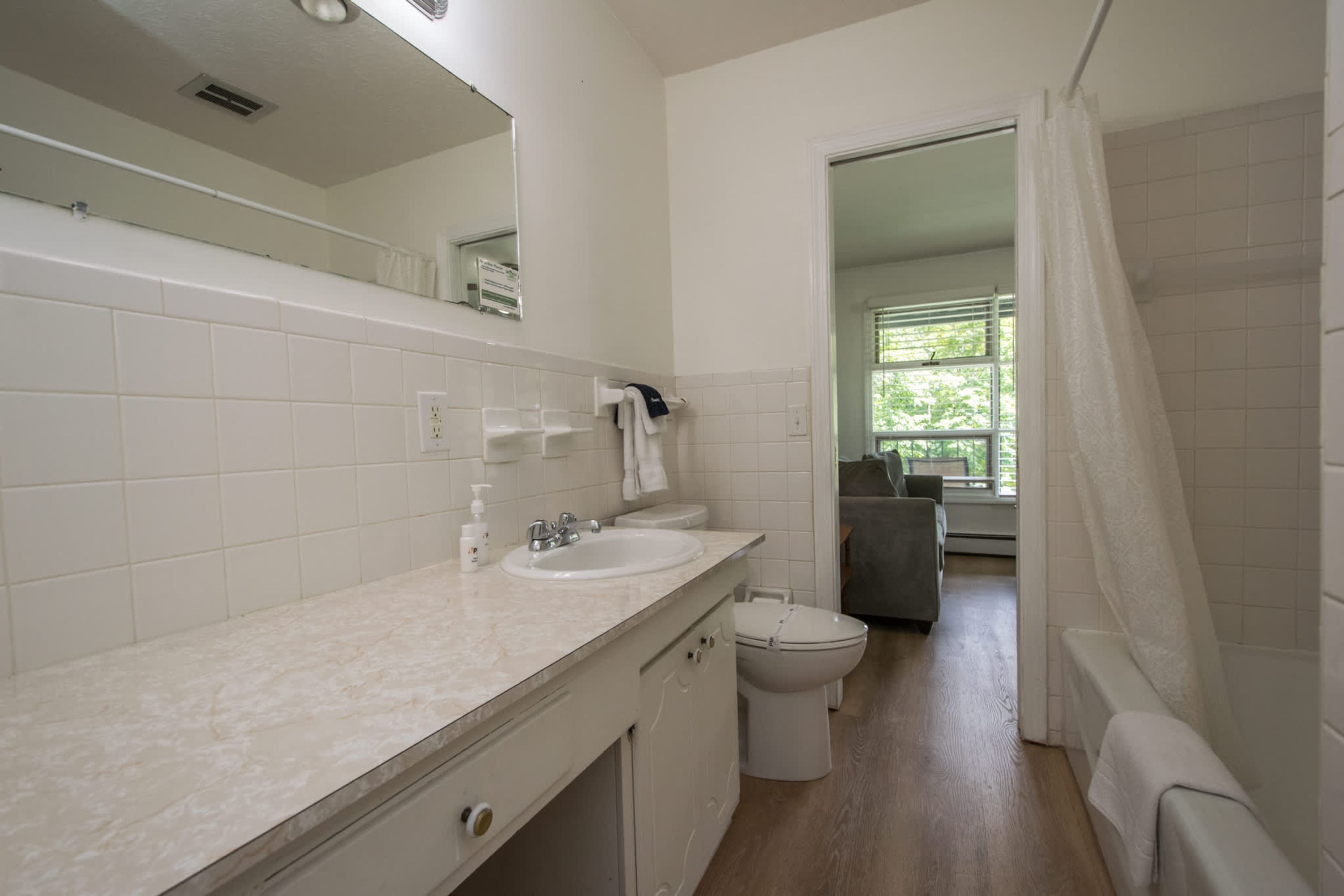 Une salle de bain avec un lavabo blanc, un miroir et des toilettes.