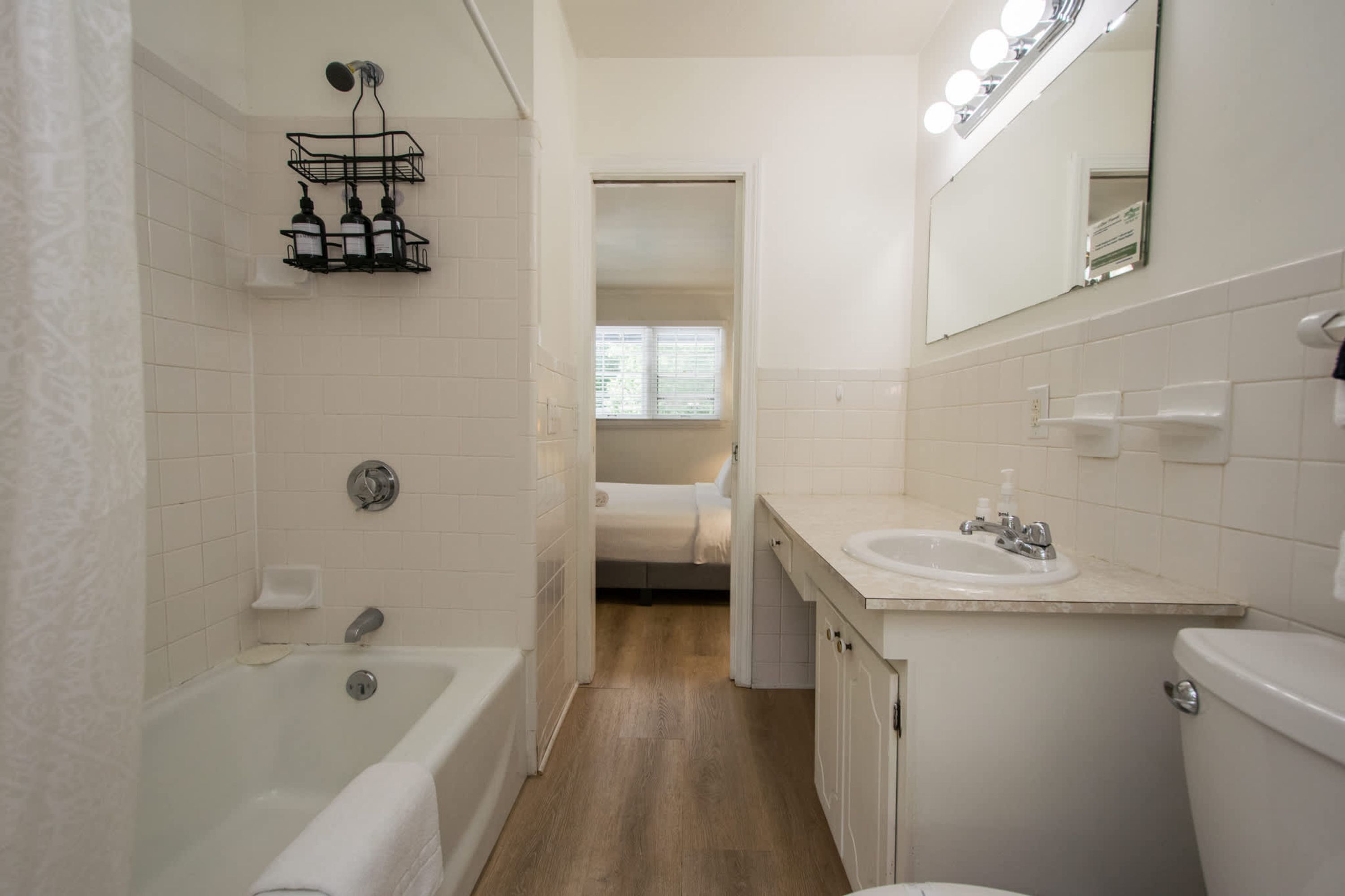 A modern bathroom with a bathtub, toilet, sink, and a mirror with lights.