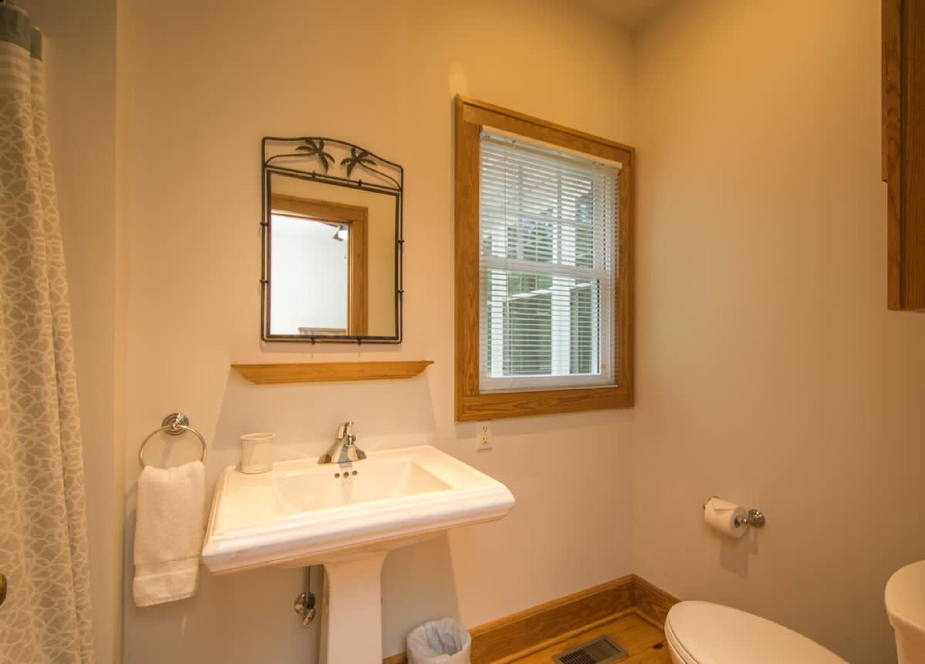 A bathroom with a sink, mirror, window, and toilet.