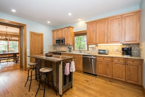 A kitchen with wooden cabinets, a granite countertop, a stainless steel dishwasher, and a bar area with stools. - Lakefront 3BR w Private Dock Firepit Free Tix (Mill Spring)