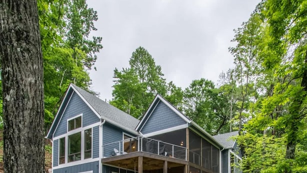 Une maison à deux étages avec une terrasse en bois menant à l’entrée.