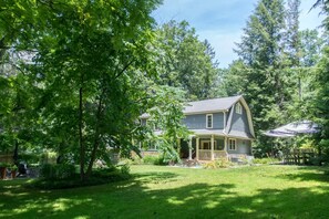 A house with a porch, surrounded by a well-maintained lawn and trees. - Historic 4BR Colonial w Pool Table Fire Pit (Hendersonville)