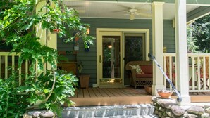 A porch with a wooden deck, a stone wall, and a door leading to a room. - Historic 4BR Colonial w Pool Table Fire Pit (Hendersonville)