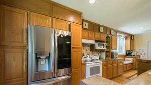 A kitchen with wooden cabinets, stainless steel appliances, and a granite countertop. - Historic 4BR Colonial w Pool Table Fire Pit (Hendersonville)