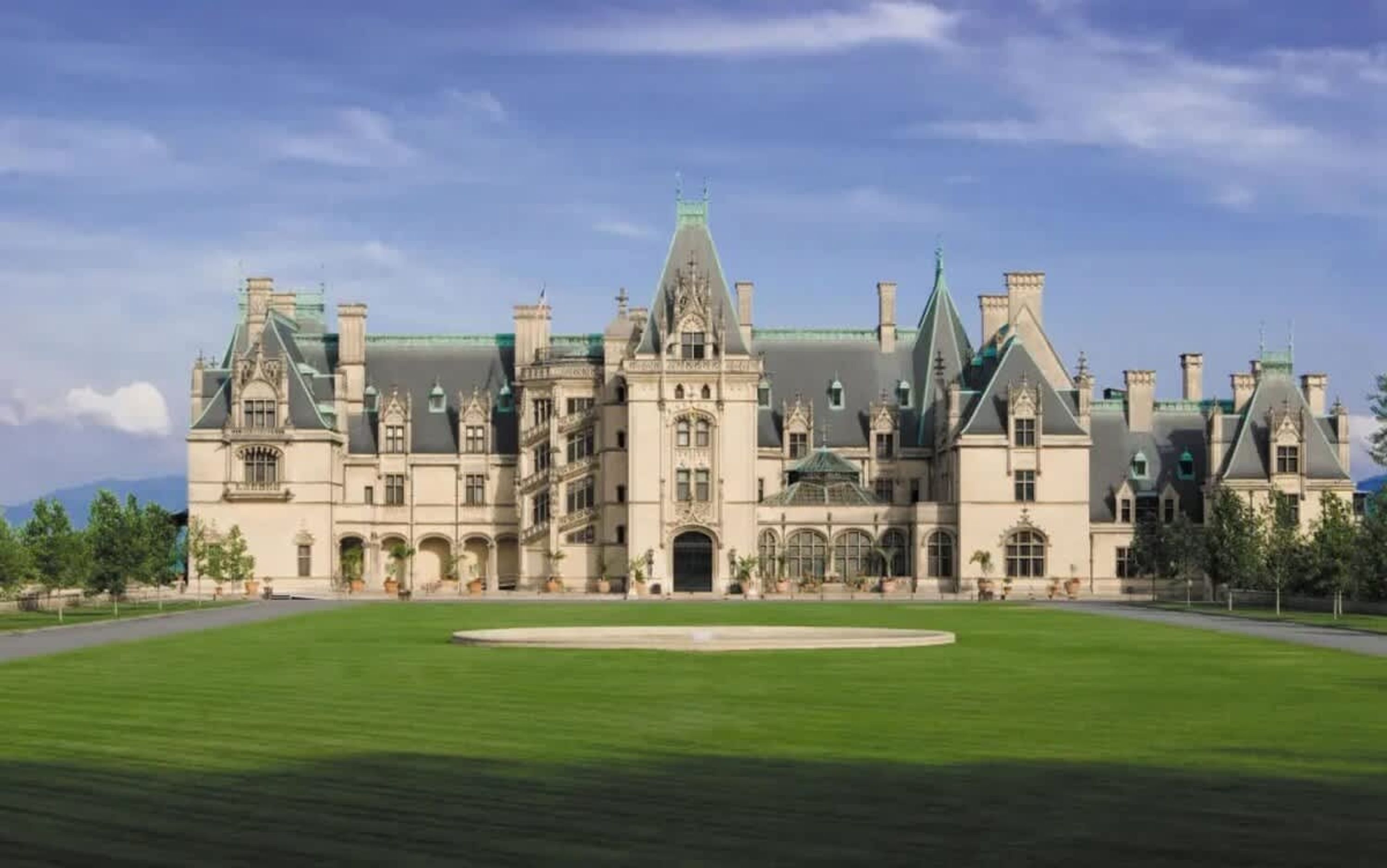 A large, historic building with a symmetrical facade, multiple chimneys, and a central entrance.