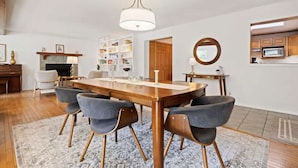 Un coin repas avec une table et des chaises en bois, un lustre et une bibliothèque en arrière-plan.