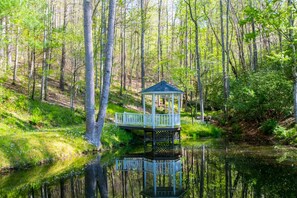 A gazebo structure with a white railing, surrounded by a forest and a body of water. - Rustic 3BR w Private Pond Firepit Near Trails (Hendersonville)