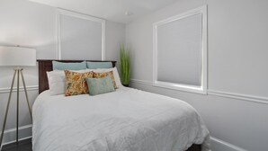 A bedroom with a large bed, white walls, and two windows with blinds. - Modern 1BR w Workspace Walk to Shops Parks (Asheville)