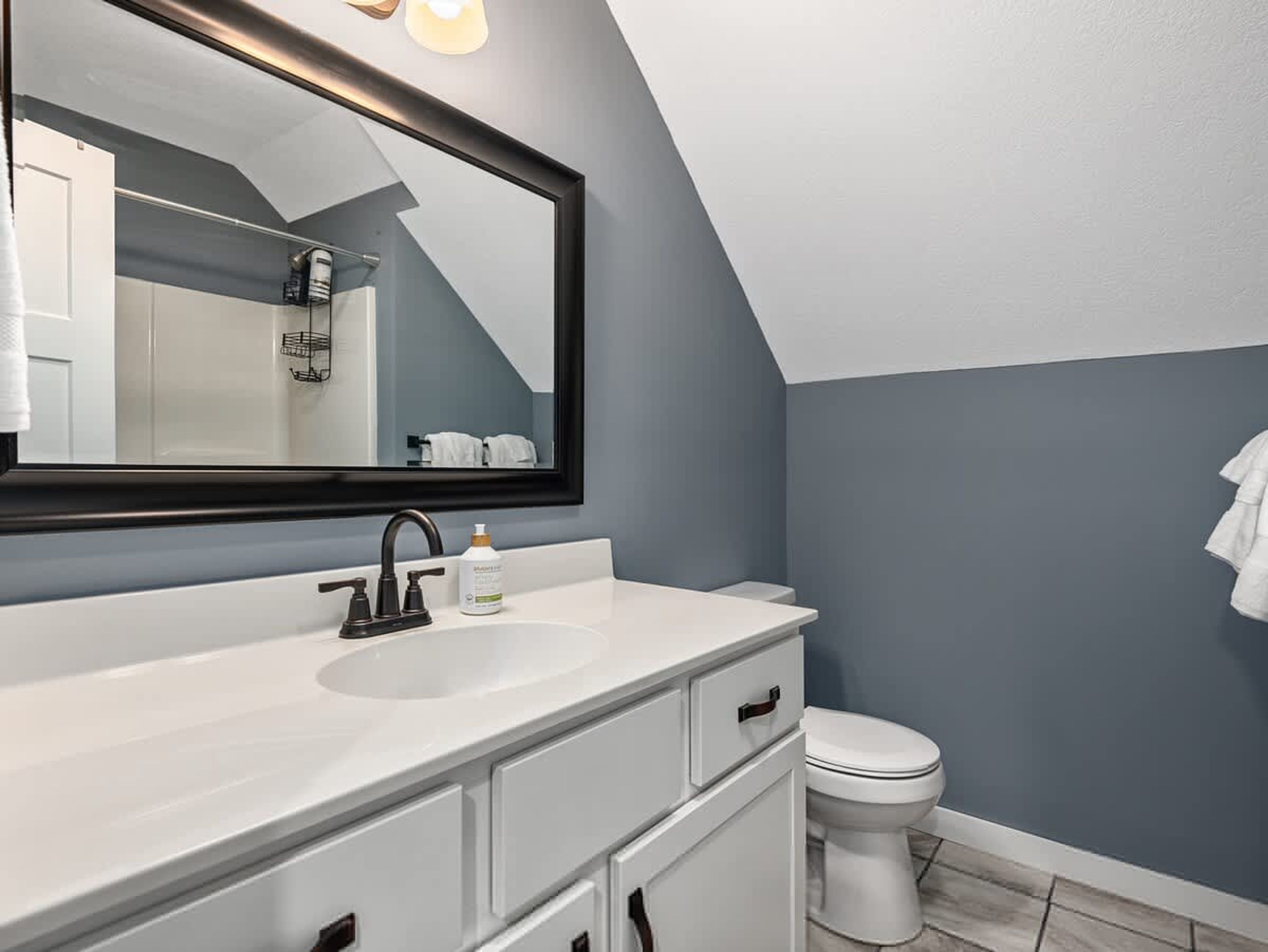 A modern bathroom with a white vanity, a large mirror, and a white toilet.