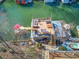 Una casa con terraza con vista a un cuerpo de agua, piscina y un pequeño jardín.