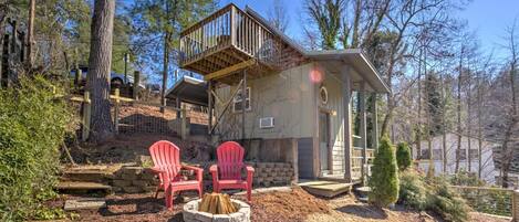 A cabin with a deck, two red Adirondack chairs, and a fire pit.
