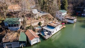 A waterfront property with multiple buildings, including a house with a green roof and a dock extending into the water. - Dog Friendly Tiny House On Lake Lure Private Dock (Lake Lure)