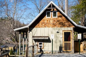 A small wooden cabin with a sloped roof, a wooden door, and a small porch area. - Dog Friendly Tiny House On Lake Lure Private Dock (Lake Lure)