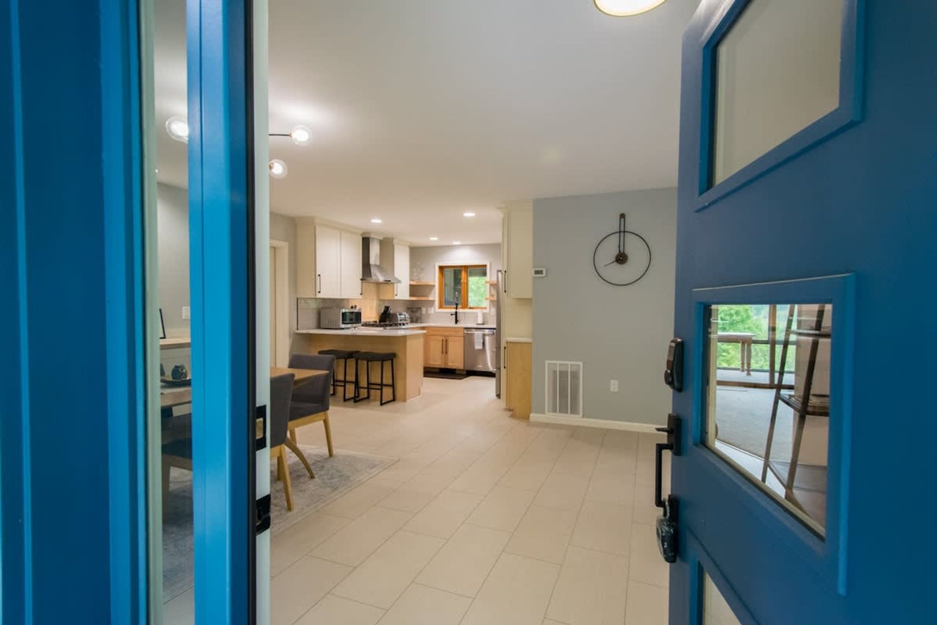 Een moderne keuken met een eethoek, een blauwe deur en uitzicht op de omgeving.