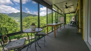 Een overdekt balkon met uitzicht op bergen en bomen.