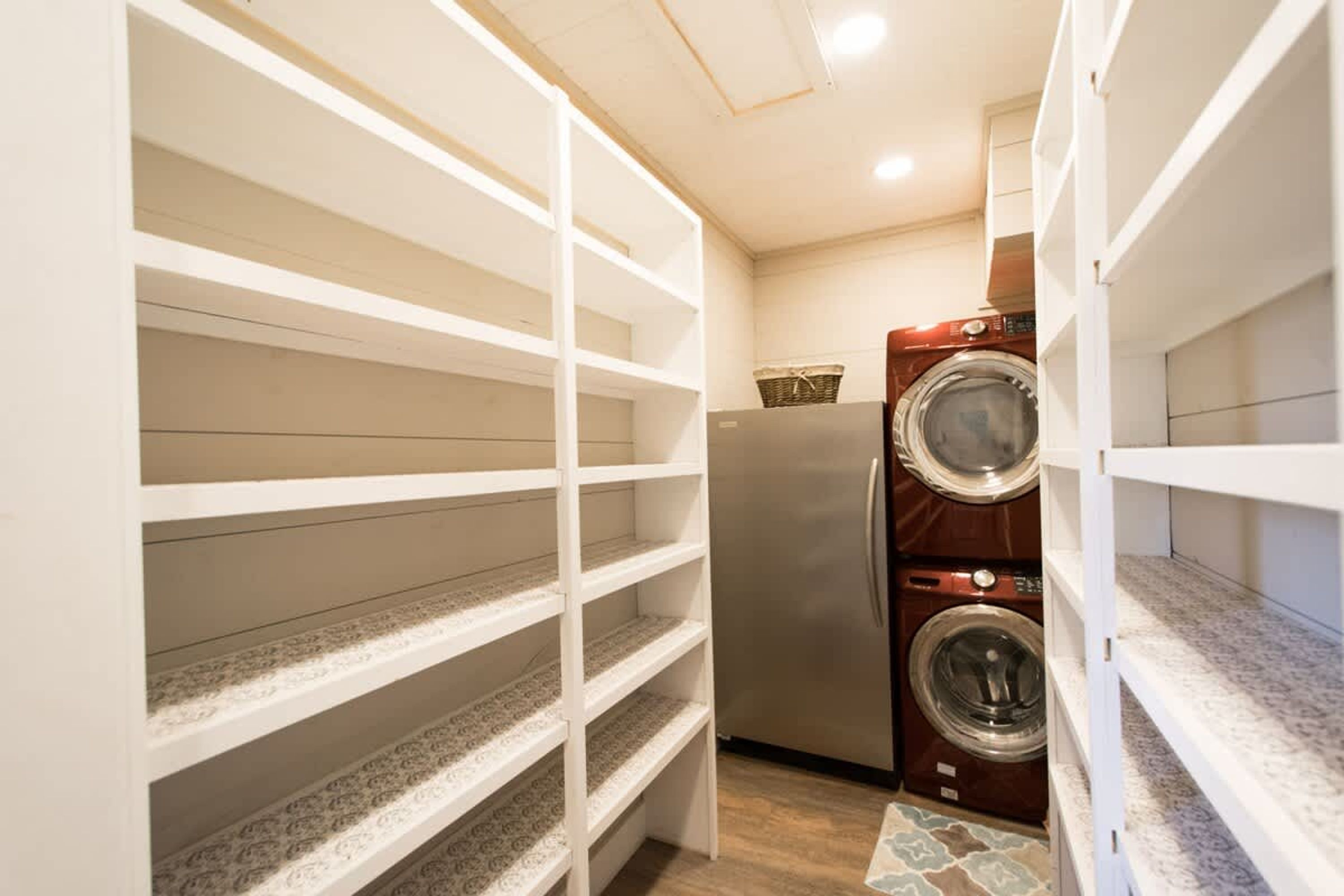 A laundry room with a washing machine and dryer, wooden shelves, and a patterned floor.