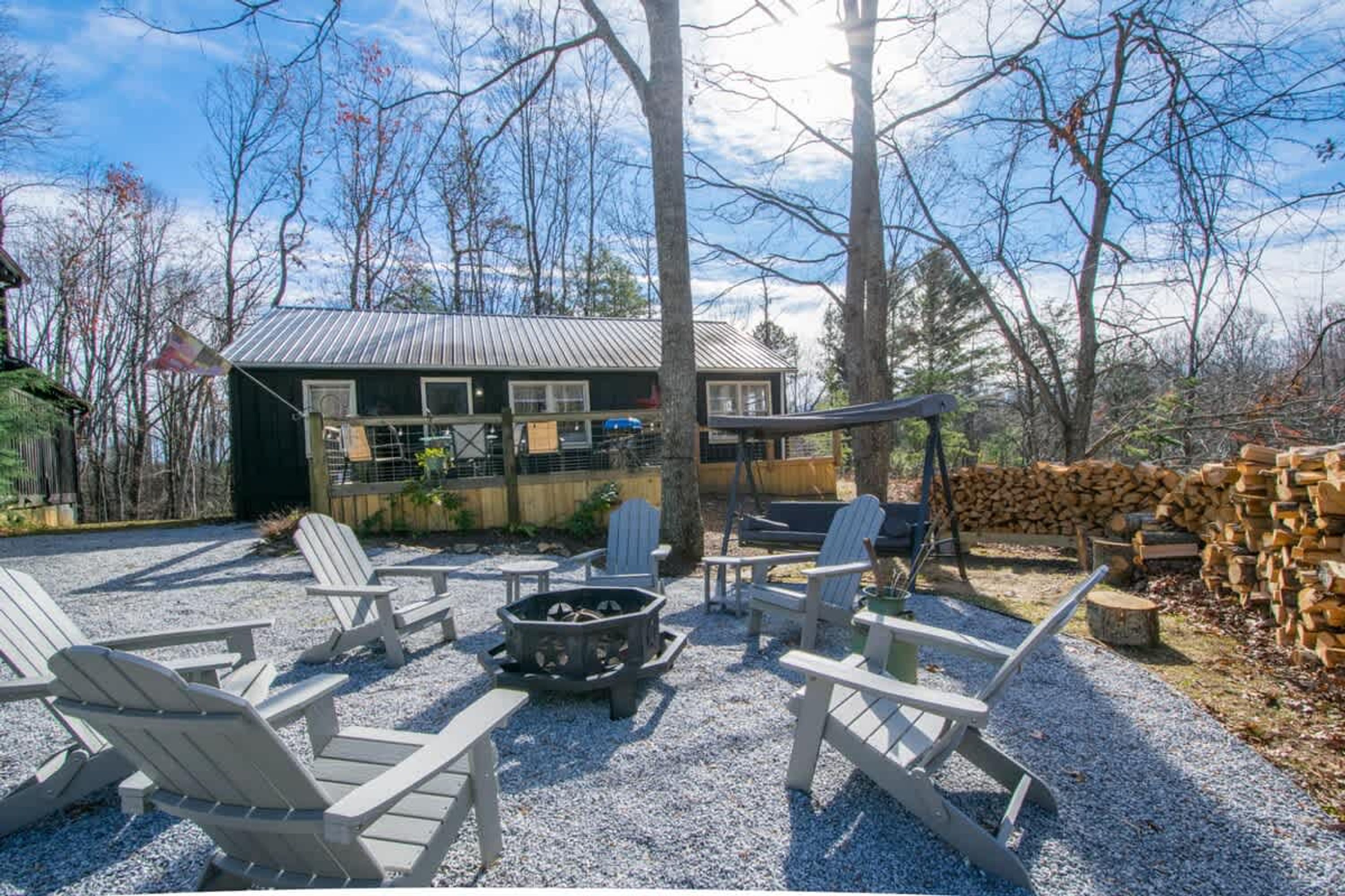 A patio area with Adirondack chairs, a fire pit, and a grill.
