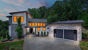 A modern two-story house with a stone facade, a garage, and a well-maintained lawn. - Luxe 5BR w Home Theater Pool Table Firepit (Alexander)