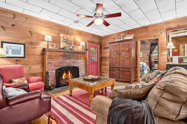 A cozy log cabin interior with a fireplace, leather furniture, and wooden walls. - Lakeside 4BR Mountain Views Firepit Game Room (Lake Lure)