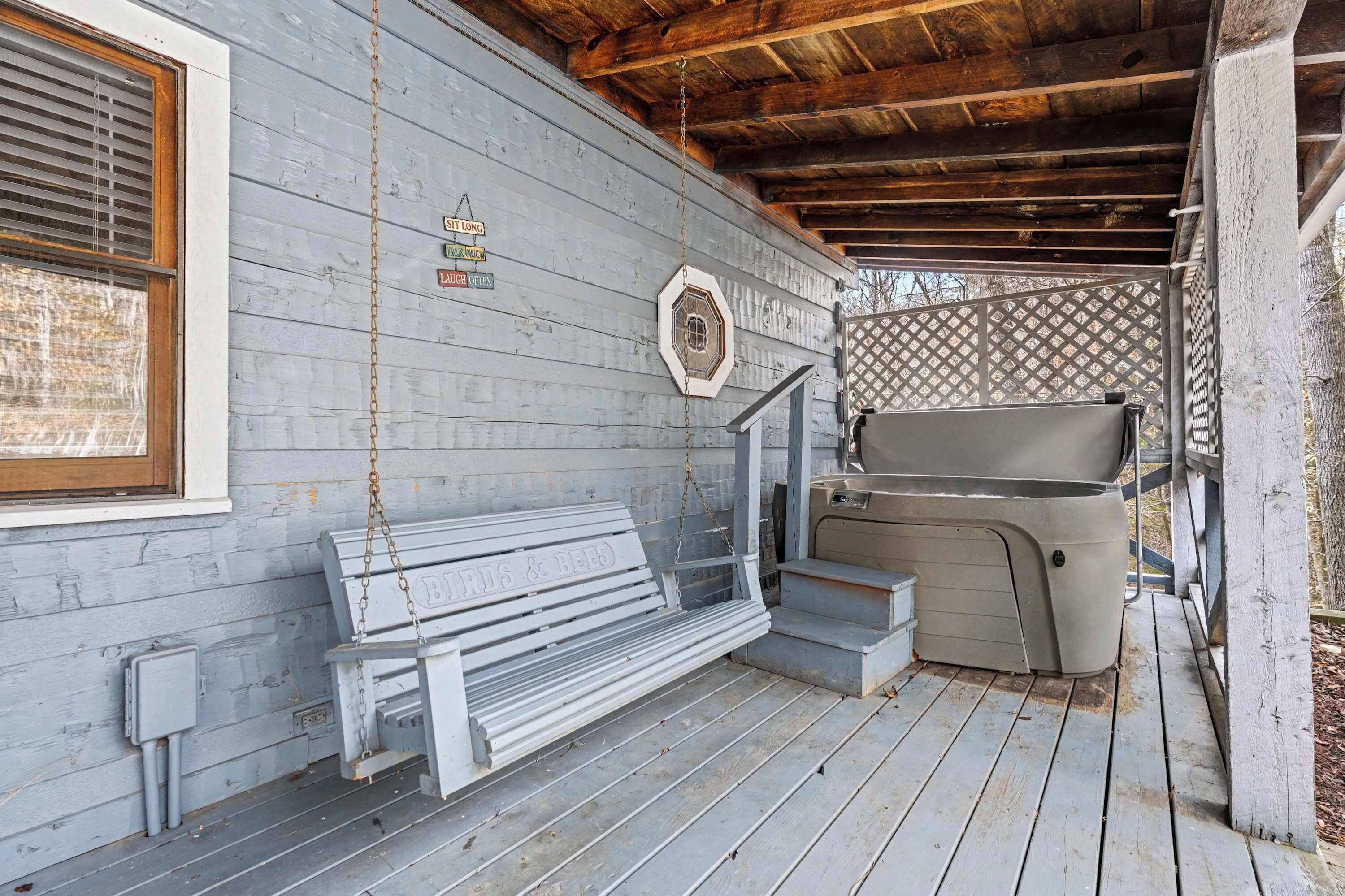 Une véranda en bois avec un banc, un jacuzzi et une lanterne décorative.