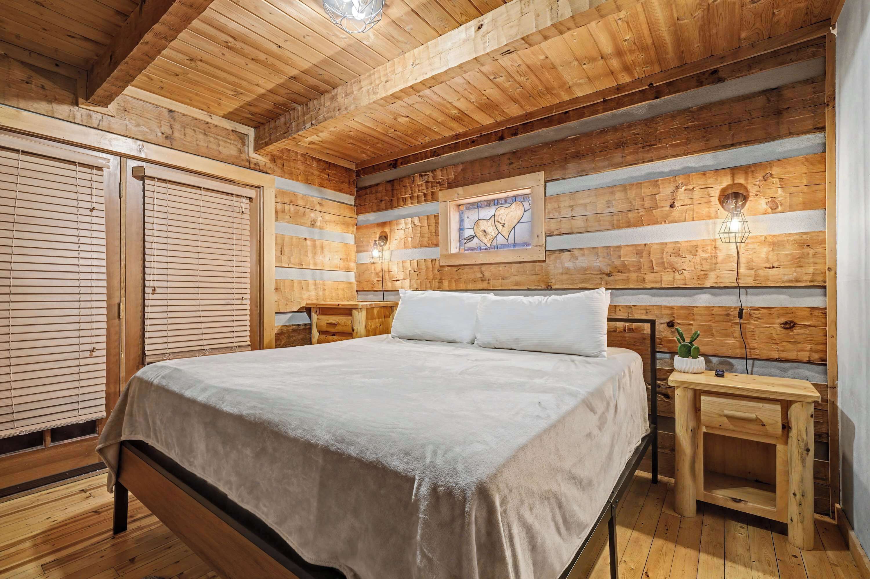 Um quarto de madeira com uma cama, paredes de madeira, um quadro emoldurado e uma mesa de cabeceira.