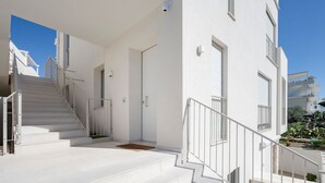 Un edificio moderno con paredes exteriores blancas, una escalera con barandillas de metal y un cielo despejado.