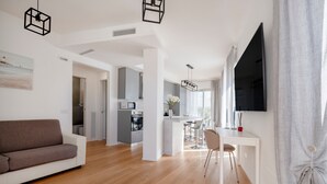Una sala de estar moderna con sofá, comedor, cocina y un amplio ventanal.