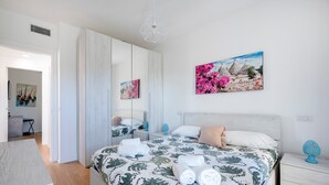 Un dormitorio con cama, mesitas de noche, armario y un cuadro en la pared.