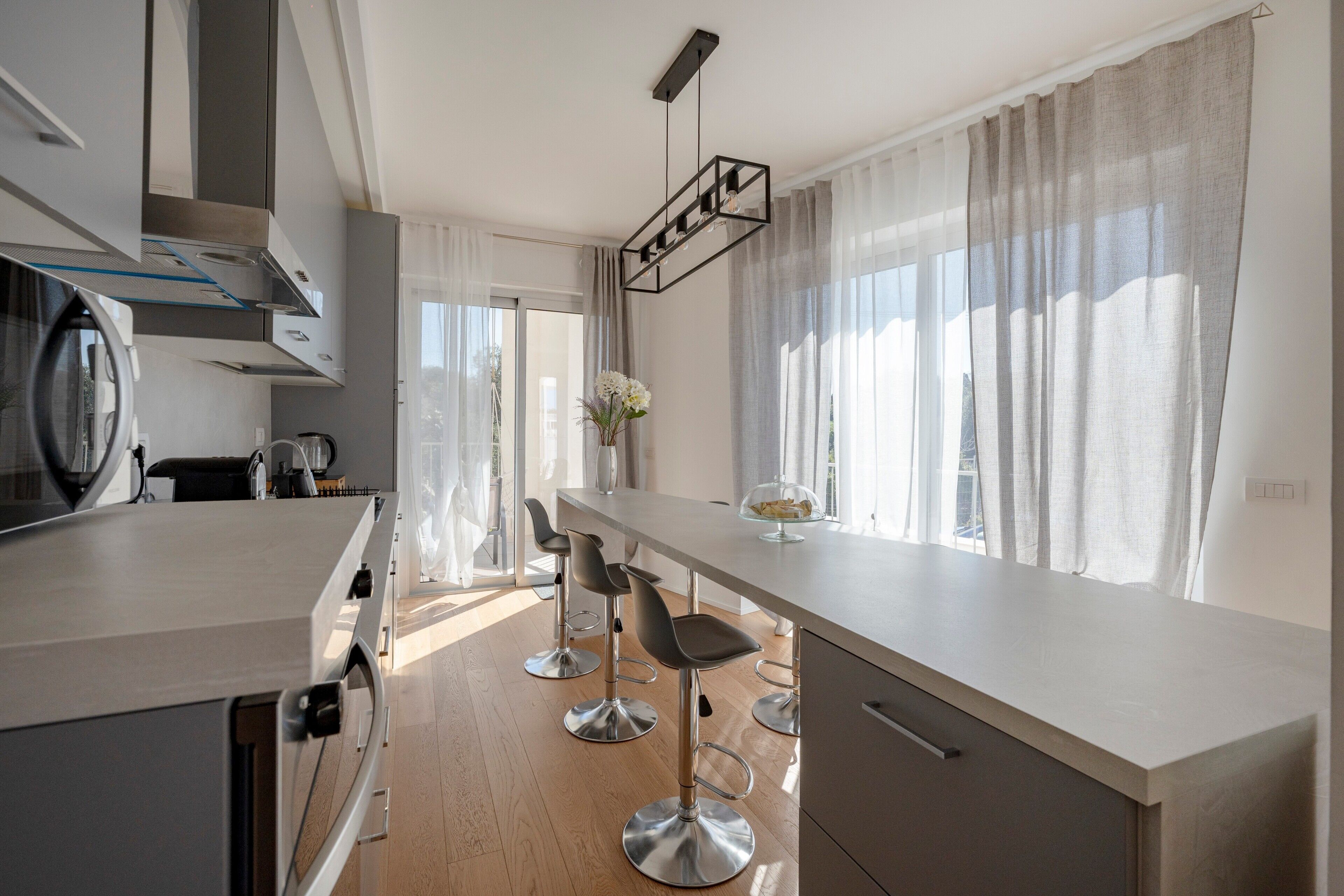 Una cocina moderna con una isla central, taburetes de bar y vistas al exterior.