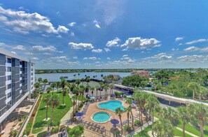 A resort with a central pool, palm trees, and a view of a body of water. - Harbor Towers 632 - Tropical Sands Accommodations (Siesta Key)