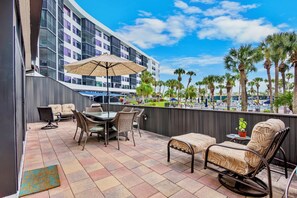 A rooftop patio with outdoor furniture, a table, and a large umbrella. - Harbor Towers 131 - Tropical Sands Accommodations (Siesta Key)