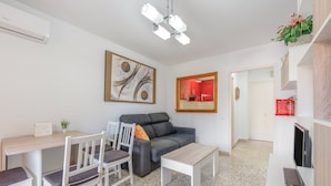 Een moderne woonkamer met een grijze bank, witte stoelen, een salontafel en een eettafel.