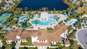 An aerial view of a resort with a large swimming pool, tennis courts, and a lake. - Go 17 Windsor at Westside (Kissimmee)