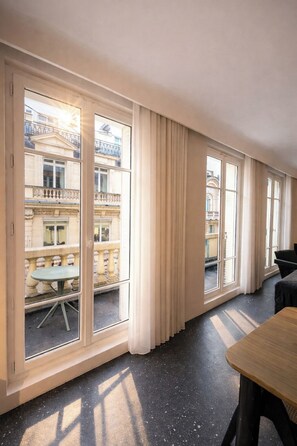 Ein Hotelzimmer mit großen Fenstern, einem Esstisch und Blick auf die Stadt.