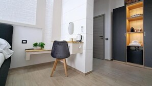 Een moderne slaapkamer met een bed, een bureau, een stoel, een kledingkast en een kleine plant.