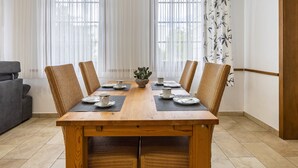 Comedor con mesa de madera, seis sillas y un centro de mesa con planta.