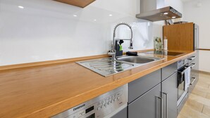 Una cocina moderna con un lavamanos de acero inoxidable, encimera de madera y electrodomésticos integrados.