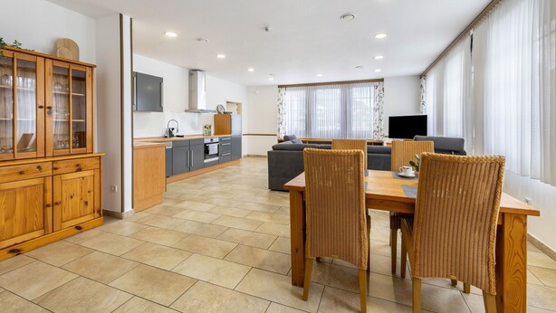 Una sala de estar moderna con comedor, cocina y un amplio ventanal con cortinas.