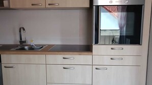 A modern kitchen with light wood cabinets, stainless steel appliances, and a built-in oven. - Cozy vacation apartment in the countryside (Wertheim)