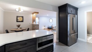 Una cocina moderna con una isla grande, armarios oscuros y electrodomésticos de acero inoxidable.