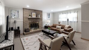 Una sala de estar con chimenea, un conjunto de sofás, una mesa de centro y un televisor.