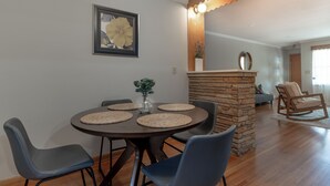 Un comedor con una mesa redonda, seis sillas y una pared decorativa de piedra.