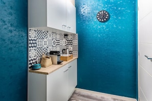Une cuisine avec des carreaux décoratifs, une horloge et un plan de travail sur lequel sont disposés divers objets.