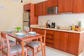 Eine kompakte Küche mit Holzausstattung, einer Mikrowelle, einem Kühlschrank, einem Spülbecken und einem Essbereich mit Tisch für zwei Personen.