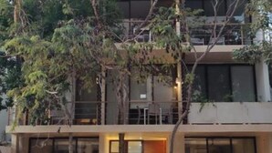 Ein mehrstöckiges Gebäude mit einem Balkon im oberen Bereich, großen Fenstern und einer Eingangstür im Erdgeschoss.