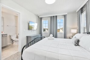 Une chambre d’hôtel avec un grand lit, un bureau avec une chaise, un téléviseur à écran plat, une fenêtre avec des rideaux et une vue sur l’extérieur.