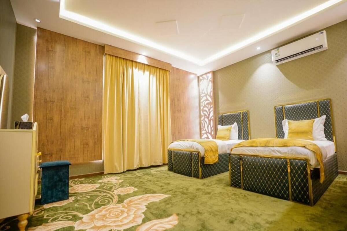 A hotel room with two beds, a desk, and an air conditioning unit.
